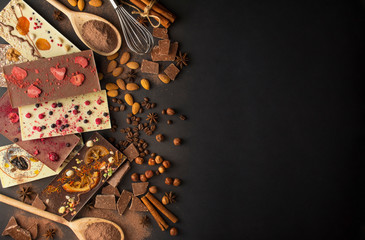 Handmade chocolate with berries, nuts, dried fruits on a dark background. Black and white chocolate. Chocolate bar. Chocolate background. Recipe. Copy space.