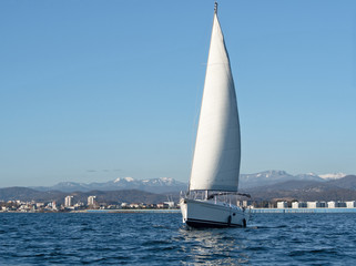 White sailing yacht on sea water at coast background at sunny summer day