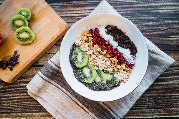 Healthy and organic smoothie bowl with seeds and fruits on a wooden table. Top view.