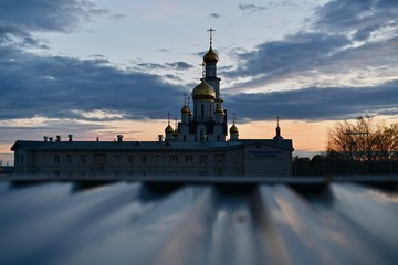 View of the cathedral and the Orthodox gymnasium at dusk at sunset against the background of clouds diverging.