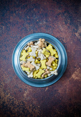 dry pet food in a metal bowl on lava background, top view