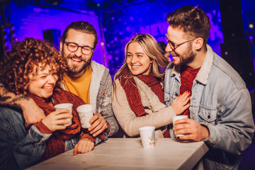 Friends drinking hot wine and having fun on outdoor concert. Celebrating new year