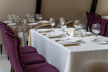 Chic and elegant, gold-plated cutlery and white plates, table setting with empty plates. Beautiful armchairs and a fully covered table.