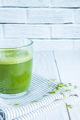Japanese green tea Matcha in a transparent glass mug close up on a white wooden table against a brick wall