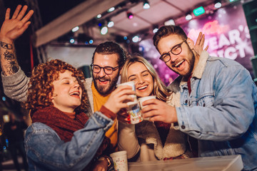 Friends drinking hot wine and having fun on outdoor concert. Celebrating new year