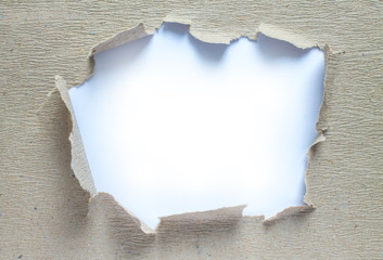 Frame made of textured old gray paper with a torn hole in the middle and a white background for