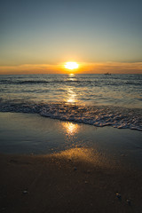 Romantischer Sonnenuntergang, brennender Himmel auf Sunibel Island mit Möven am Himmel und Boot am Horizont