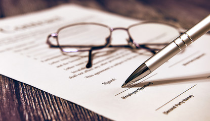 Contract with glasses and a pen on a wooden background