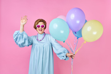 Cute old woman with balloons in blue suit disco dancer. Animator of children's parties, funny clown...
