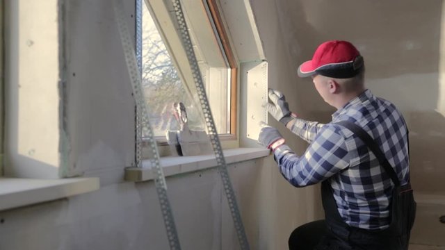home improvement handyman installing window in new build attic by using leveler and laser leveler