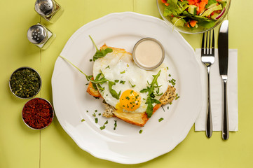 Delicious breakfast. Toast with egg, salad and spices on a green background
