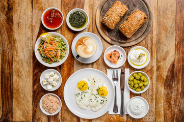 Classic breakfast with a cup of cappuccino and meals on wood background