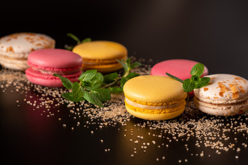 Macarons or cake macaroon with mint on black background with copy space for text. Colorful French or Italian dessert. Sweet food