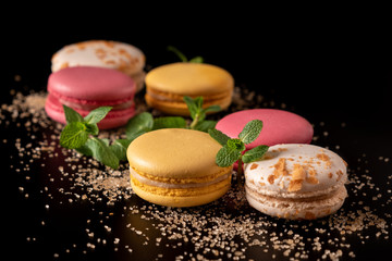 Macarons or cake macaroon with mint on black background with copy space for text. Colorful French or Italian dessert. Sweet food