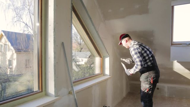 home improvement handyman filling drywall with filler in new build attic