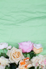 Various different flowers with vivid colours on rumpled green background.
