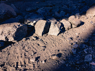 Pieces of coal lie on the ground in a strip of sunlight.