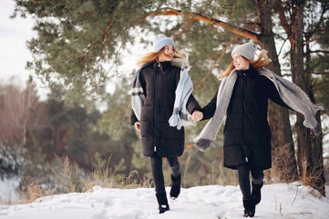 Fototapeta na wymiar Cute girls walking in a winter park. Sisters have fun with snow. Ladies in a cute hats