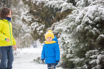 Sweet toddler boy, playing with snow on playground