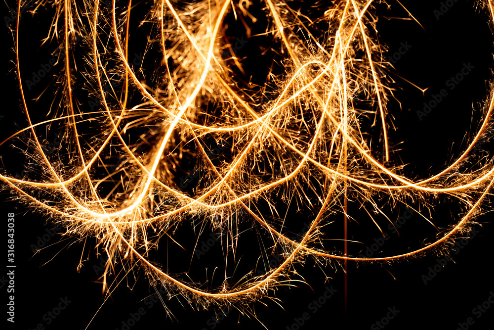 Wall mural abstract pattern of sparks and bright light beams of golden color on a black background
