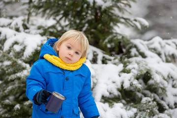 Sweet toddler boy, playing with snow on playground