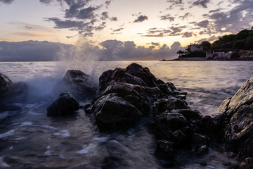 Wave hitting the rocky shoreline at sunrise