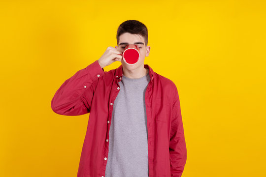 young teenage man drinking coffee or drinking isolated on color background