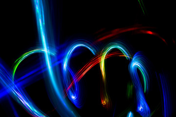 Abstract color pattern of luminous stripes on a black background, bright and smooth color streaks