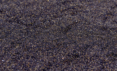 Black volcanic sand. Black textured background.