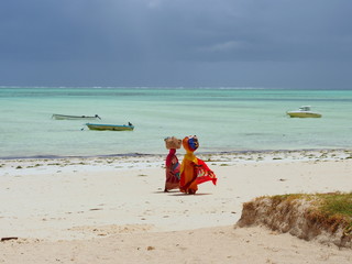 African women are walking on the Zanzibar beach