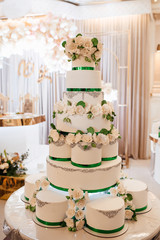 Beautiful white with green wedding cake. Rich layered wedding cake decorated with white flowers. Cake for wedding day. Beautiful wedding cake detail - traditional sweets to Bride and Groom