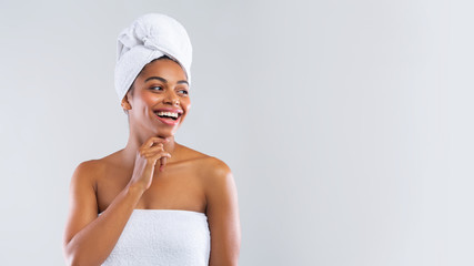 Happy black woman wrapped in towels looking at copy space