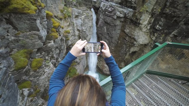A Woman records video on Phone at waterfall in Johnson Canyon