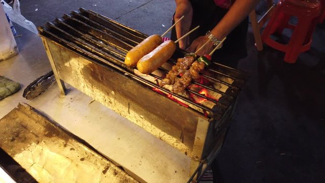 Sausages and chicken satay on grill. Thai street fod in Bangkok, Thailand.