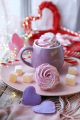 Fototapeta na wymiar Cup of coffee with meringues and marshmallows, Turkish delight on a plate, hearts, illumination, against the background of a window, homeliness, Valentine's day