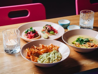 Nachos, guacamole, tacos, soup and candles on the table in cantina bar