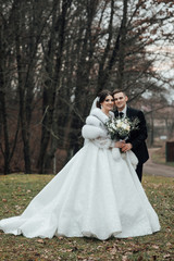 Wedding couple is walking. Bride with flower bouquet. Wedding day. Beautiful wedding couple, bride and groom, in love. The groom in a beautiful suit and the bride in a white luxury dress.
