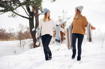 Fototapeta na wymiar Cute girls walking in a winter park. Sisters have fun with snow. Ladies in a cute sweaters
