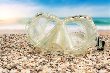 The mask for swimming underwater lies on the shore by the sea.