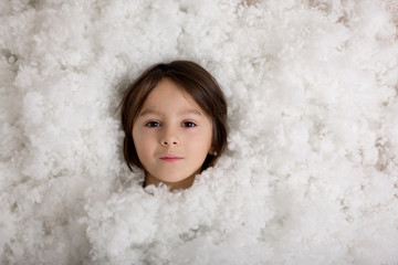 Beautiful portrait of boy, lying on the floor in a pile of cotton