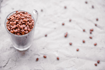 Roasted coffee beans in white cup.  Light concrete background. Top view