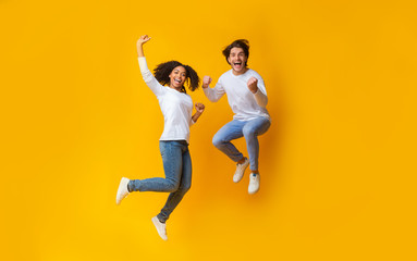 Fototapeta Cheerful girl and handsome guy jumping in air, having fun together obraz