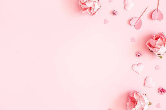 Valentine's Day background. Pink flowers, envelope, hearts on pastel pink background. Valentines day concept. Flat lay, top view, copy space