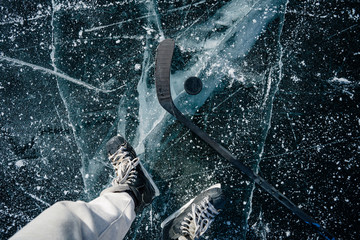 Hockey puck on a frozen pond. Ice skating in nature at sunset in winter. Travel and sports