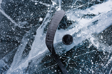 Details close up hockey puck on a frozen pond. Ice skating in nature at sunset in winter. Travel...