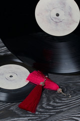 Homemade tassel earrings in red. Against the background of old vinyl records and brushed pine...