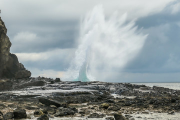Tall and strong waves crushing over the sharp cliffs of Koka Beach. Hidden gem of Flores Indonesia. The water rockets high up. Power of the nature. Big overcast. Restless sea.