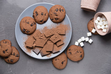 Chocolate and cocoa cookies lie on a plate; next to them lies marshmallows.