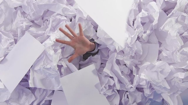 hand reaches out from a large heaps of crumpled paper the view from the top slow mo
