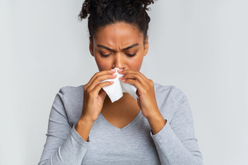 Woman touching her nose with napkin, having runny nose - obrazy, fototapety, plakaty